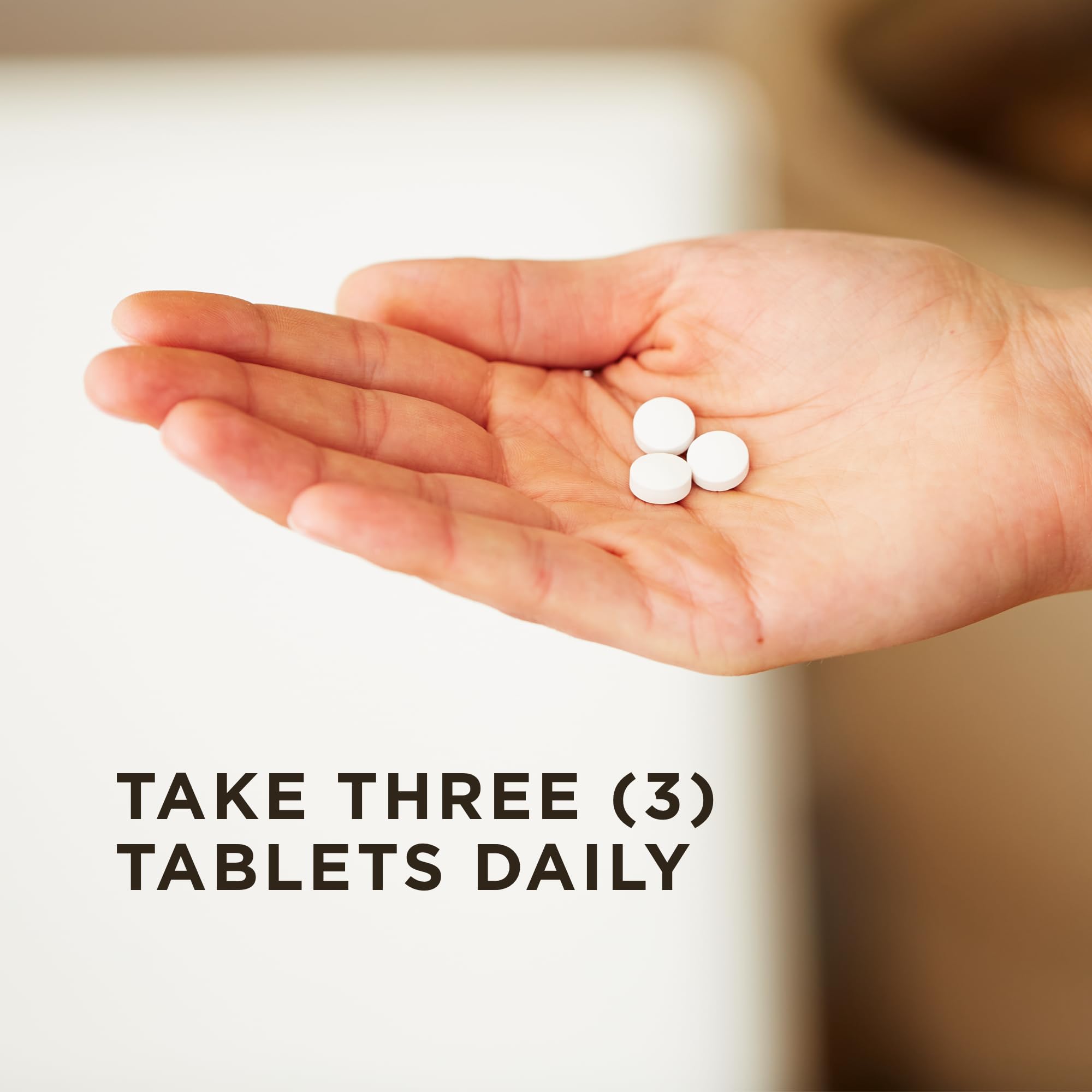 Hand holding three white round tablets in palm with dosage text take three tablets daily Solgar Magnesium with Vitamin B6 tablets