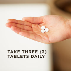 Hand holding three white round tablets in palm with dosage text take three tablets daily Solgar Magnesium with Vitamin B6 tablets