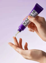 Purple eye cream tube squeezing beige cream onto a hand