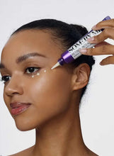 Eye cream being applied from a purple tube onto face near the eye