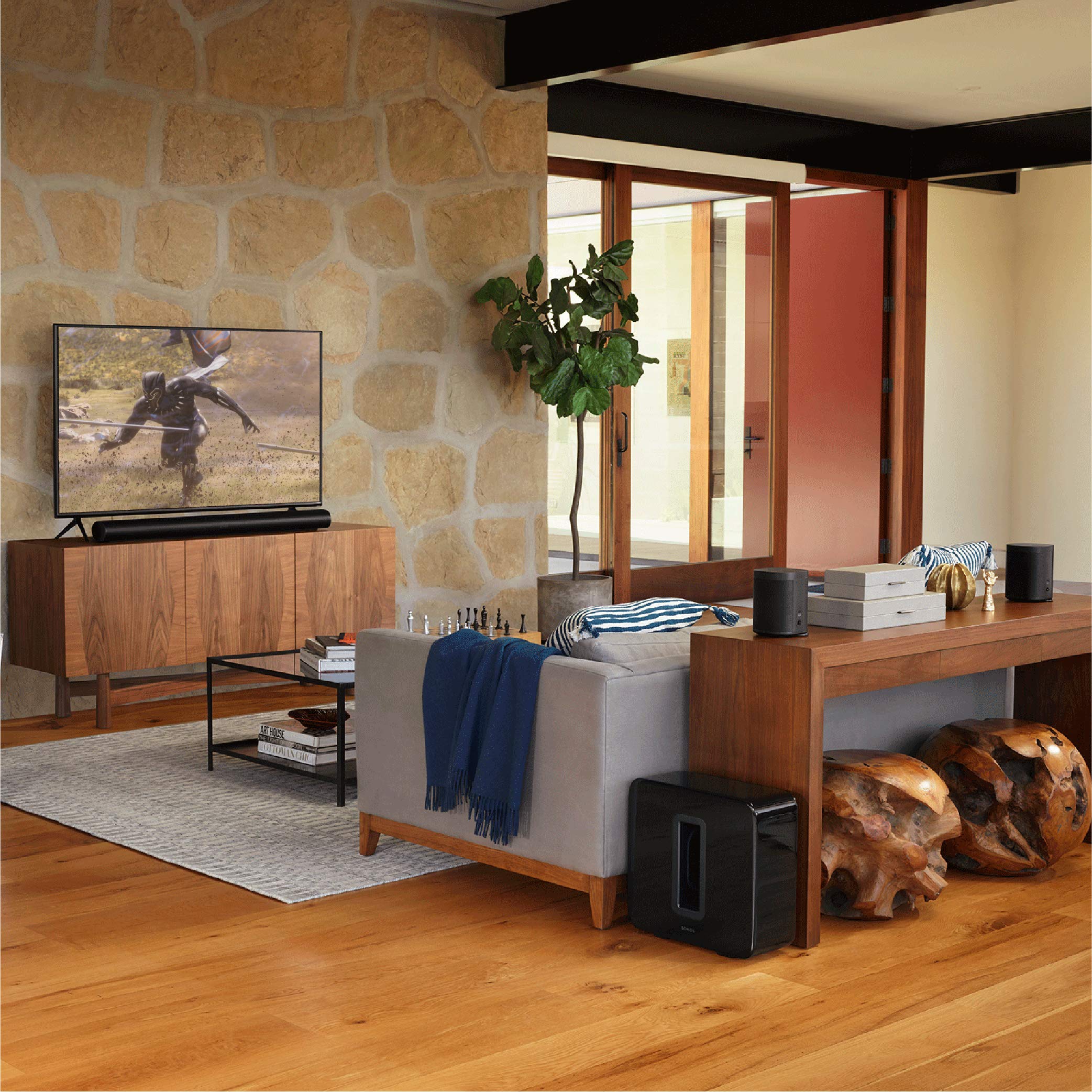 Premium smart soundbar for TV placed below a flat screen in a modern living room with wooden furniture