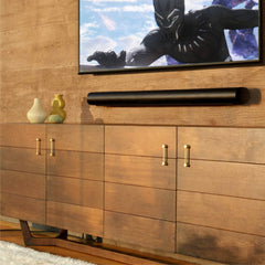 Sleek black premium smart soundbar for TV mounted on wooden wall under modern flat screen TV