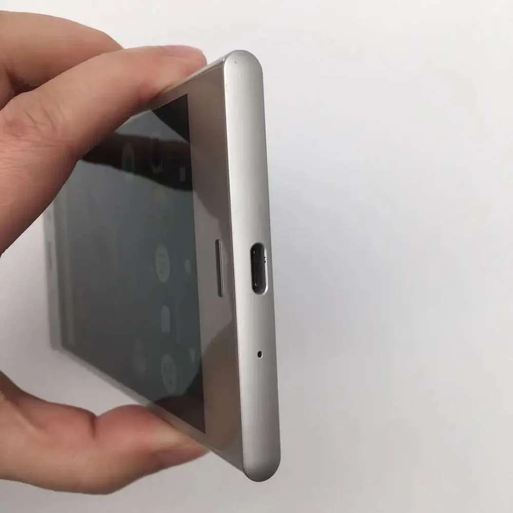 Hand holding silver Sony Xperia XZ1 unlocked smartphone showing bottom USB C port microphone hole and front screen