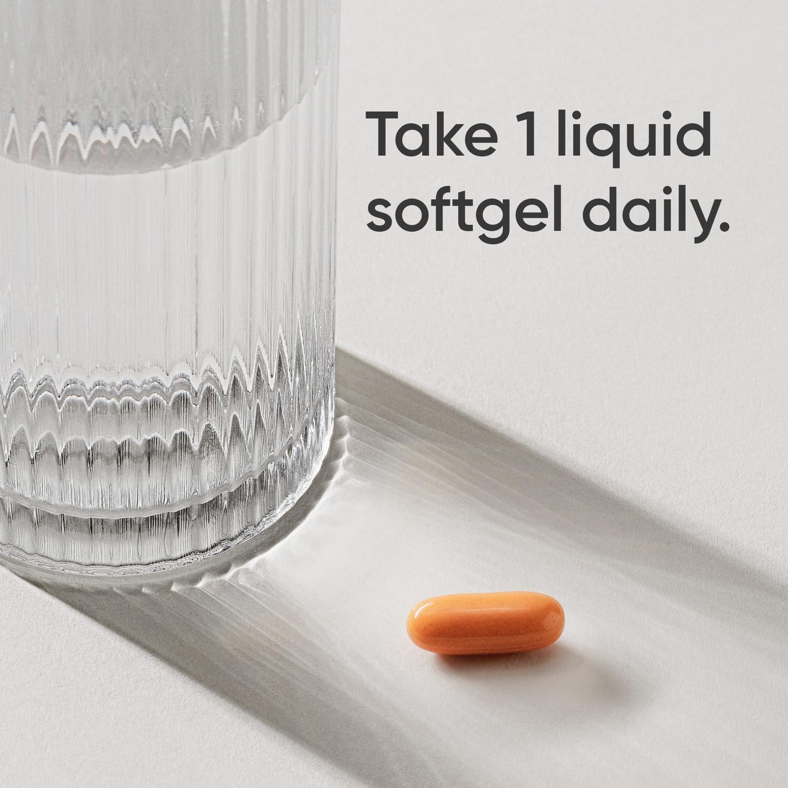 Orange liquid softgel beside glass with dosing instruction Take 1 liquid softgel daily turmeric curcumin supplement UAE