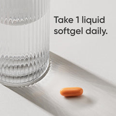 Orange liquid softgel beside glass with dosing instruction Take 1 liquid softgel daily turmeric curcumin supplement UAE