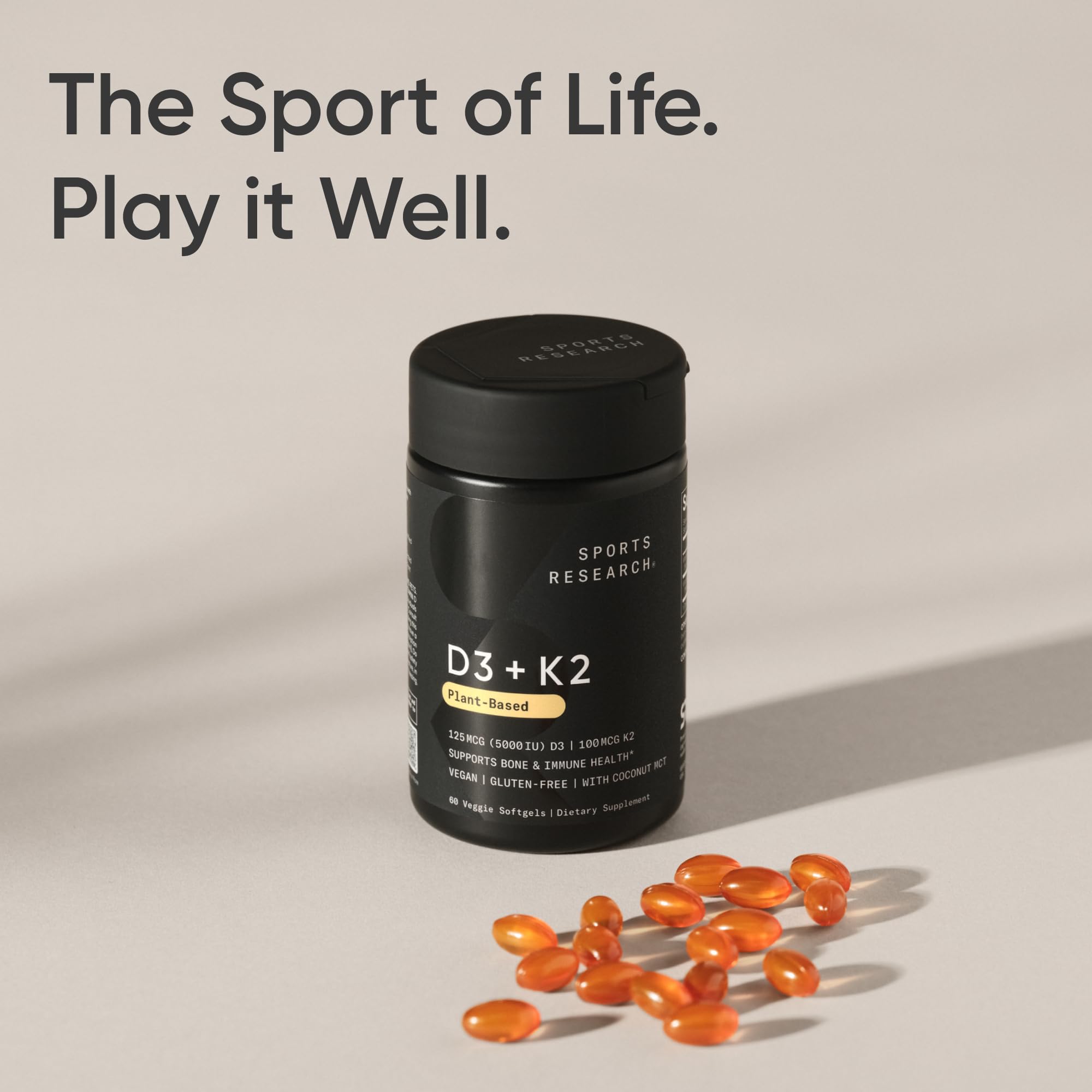 Sports Research D3 K2 bottle and scattered orange softgel capsules Vitamin K2 D3 supplement UAE for bone and immune support
