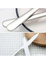 Stainless steel knife set close-up of crossed blades and rounded handle.