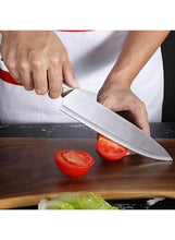 Stainless chef knife slicing tomato on a wooden cutting board