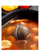 Stainless steel mesh tea infuser ball on a chain floating in hot tea