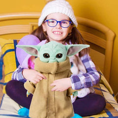 11 inch Baby Yoda plush toy held by smiling child sitting on bed with purple glasses and white hat