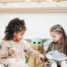 Baby Yoda-style plush toy with tan robe and mint ears, shown being held