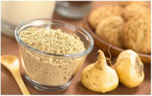 Glass bowl of beige maca powder with maca root pieces