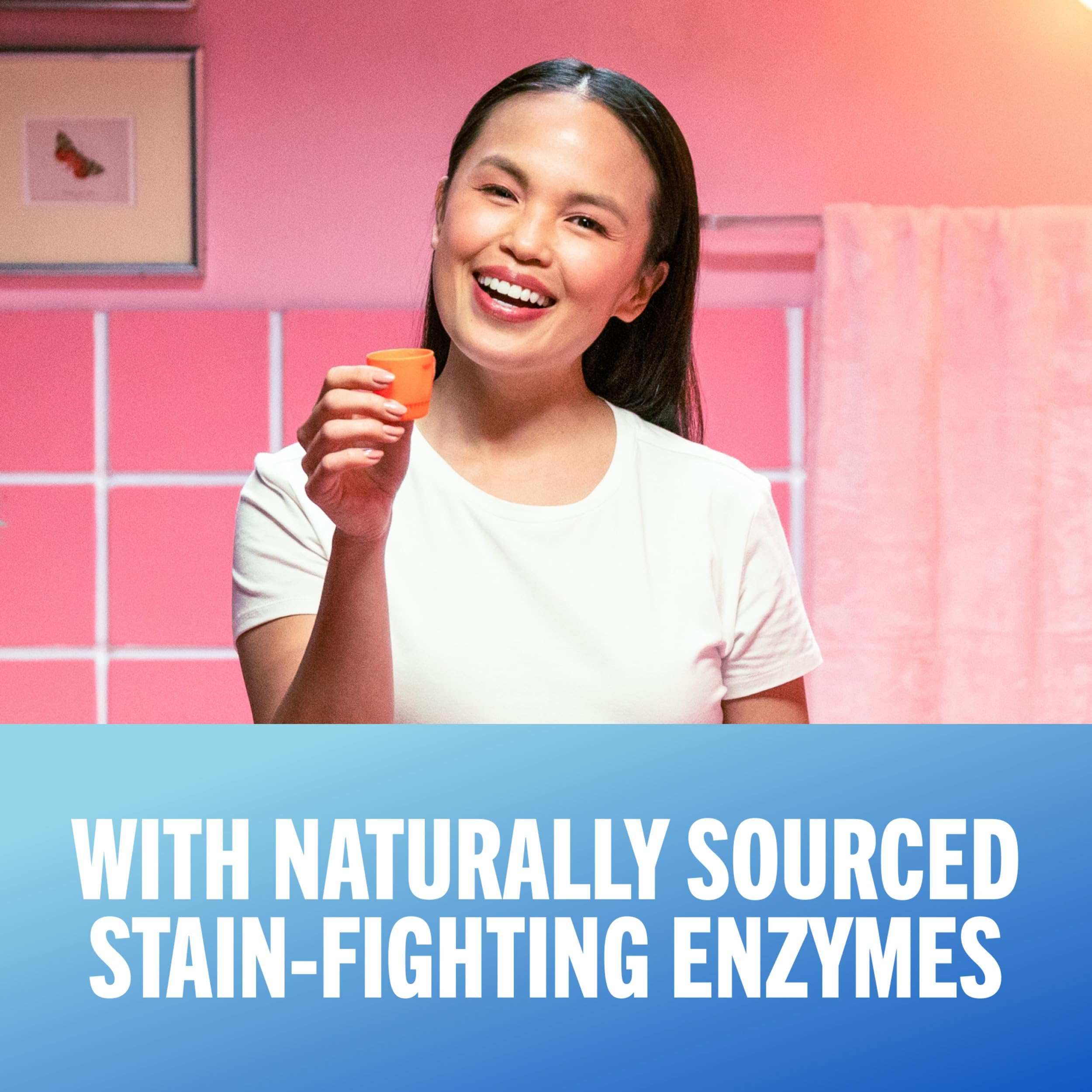 Smiling woman holding orange rinse cup in pink bathroom promoting TheraBreath whitening mouthwash UAE with stain fighting enzymes