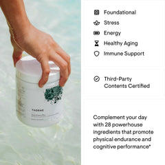 Hand holding Thorne Daily Greens Plus powder white jar over water showing label and green plant design