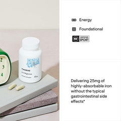 White bottle of Thorne Iron Bisglycinate supplement with two capsules on stacked books and alarm clock
