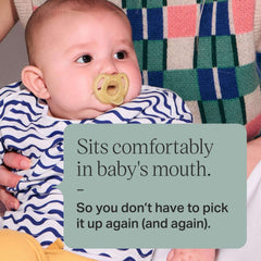 Baby using Tommee Tippee silicone soother 0-6 months with olive pacifier held by caregiver wearing patterned sweater
