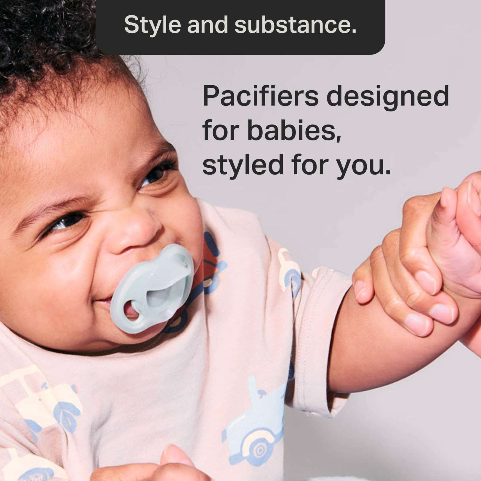 Baby using grey pacifier smiling Tommee Tippee silicone soother 0-6 months shown with adult holding hand