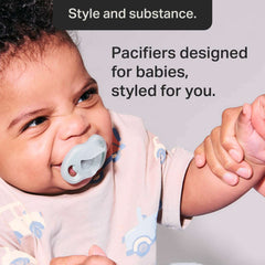 Baby using grey pacifier smiling Tommee Tippee silicone soother 0-6 months shown with adult holding hand