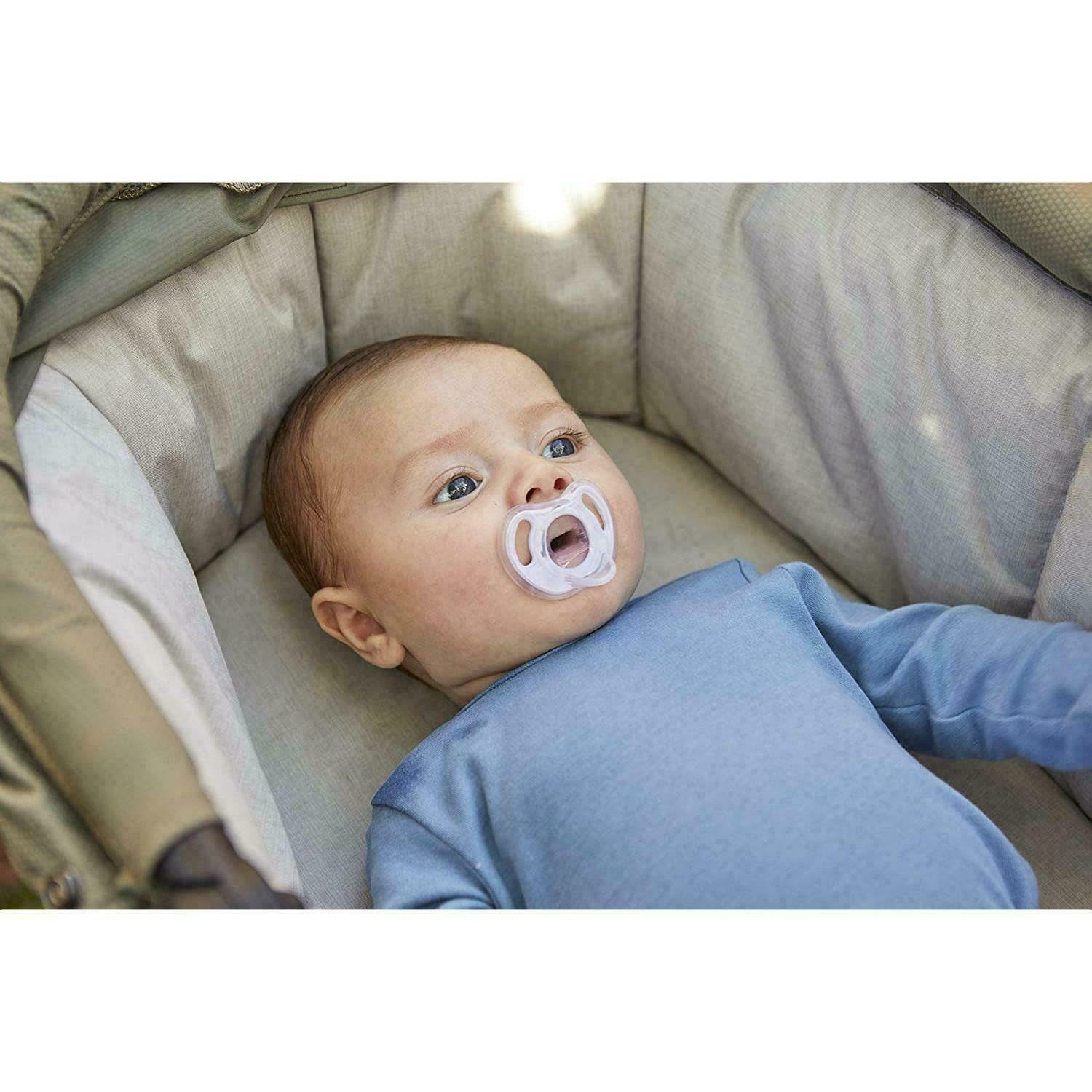 Baby lying in stroller wearing blue onesie using Tommee Tippee ultra light soother clear pacifier