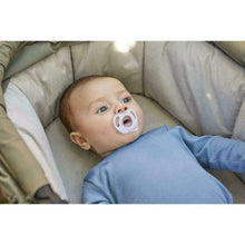 Baby with light blue silicone soother lying on padded bedding