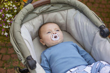 Baby in pushchair with light blue silicone soother
