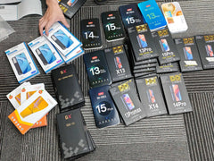 Mumzar assortment of boxed iPhone screens and parts on carpet showing multiple models iPhone OLED display replacement stock