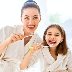 Mother and daughter in white robes brushing teeth smiling showcasing travel toothbrush kit with case for family