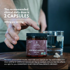 TRIBE ORGANICS Ashwagandha KSM-66 capsules UAE jar on wooden table with two capsules a glass of water and hand reaching