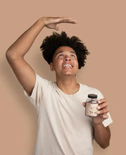 Height growth supplement gummies bottle held by smiling teen in a white t-shirt