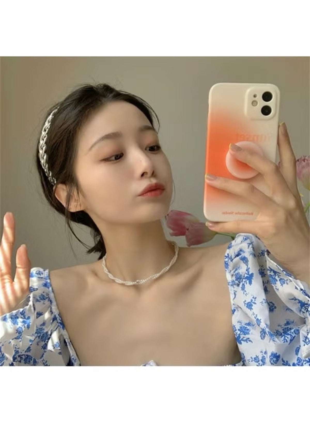 Stylish woman wearing a twisted faux pearl choker necklace with a floral top and braided hair