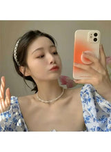 Faux pearl choker necklace on model's neck, twisted bead design