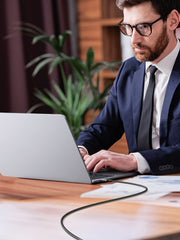 Man in suit using laptop connected with 100W fast charging braided Type C cable on wooden desk