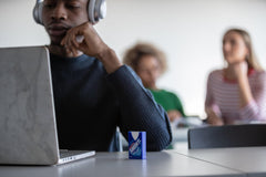 Blue Smint sugarfree mints pack on classroom desk beside student with headphones and laptop