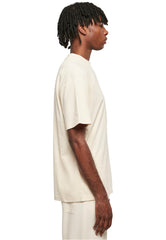 Side view of a man wearing Urban Classics tall tee for men in beige with a relaxed fit and short sleeves