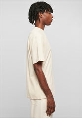 Side view of man wearing beige urban classics tall tee for men with a loose fit and short sleeves