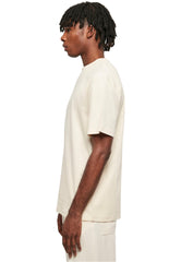 Side view of a man wearing a beige urban classics tall tee for men with a relaxed fit