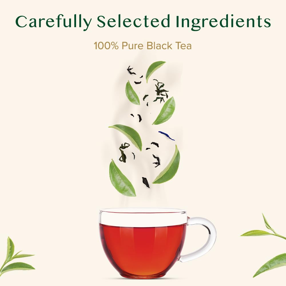 VAHDAM cup of brewed tea with loose Assam black tea leaves and fresh green leaves floating above