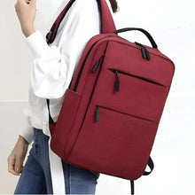 Pink diaper bag backpack worn crossbody with front zip pockets and top handle