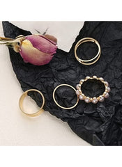 Huitich 4-piece gold ring set online with pearl and plain designs displayed on black fabric