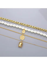 Layered gold chain and faux pearl necklaces with oval medallion and rectangle pendant