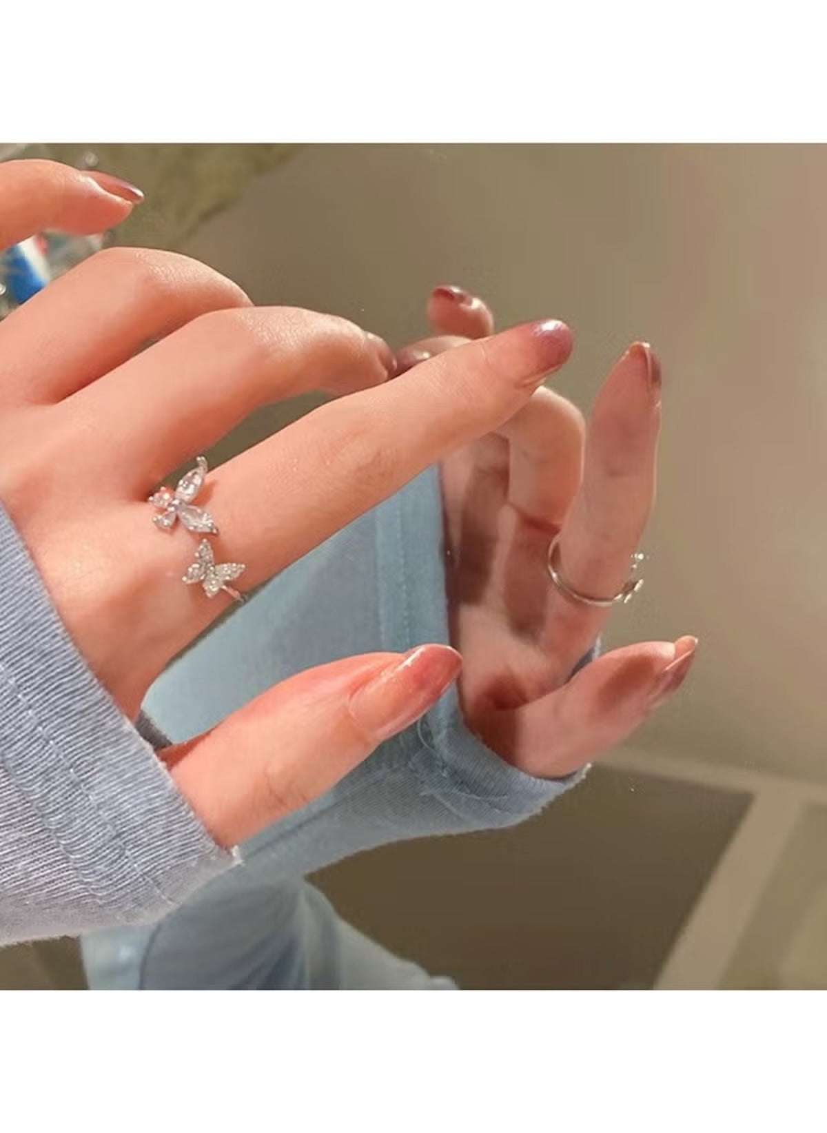 Huitich crystal butterfly ring size 6 worn on hand with long nails and light blue sleeve