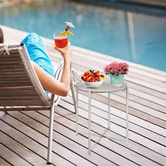 Modern side table for living room with a bowl of fruit and a pink flower pot next to a pool lounge chair