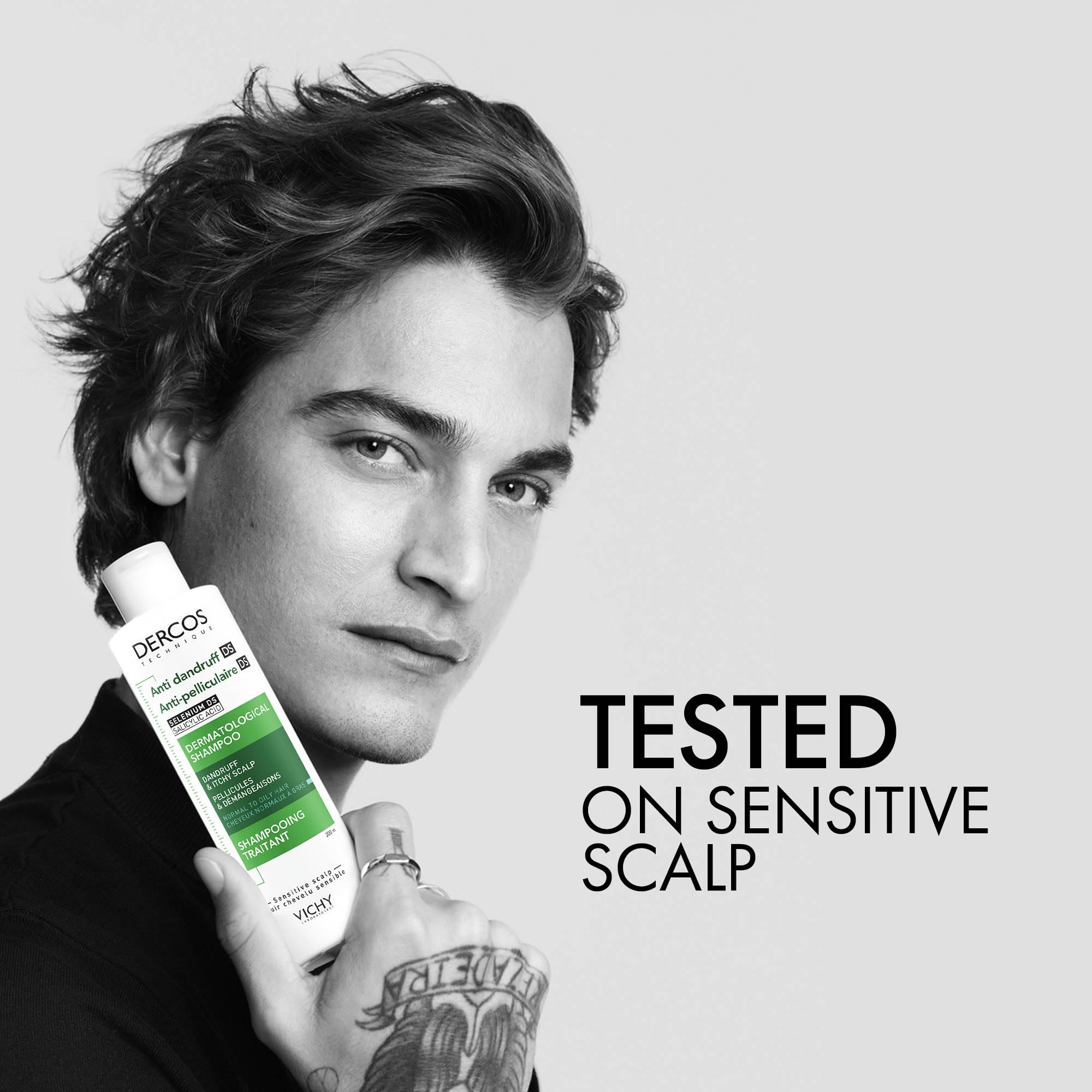 Vichy Dercos anti dandruff shampoo bottle held by a model with a sensitive scalp tested label