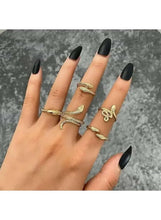 Gold-tone snake ring set with coiled designs, worn on fingers