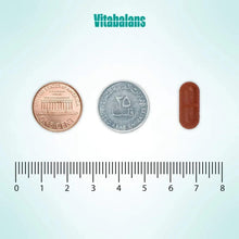 Iron supplement capsule next to coins and ruler for size comparison