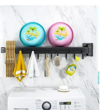 Wall-mounted foldable clothes hanger rack with multiple hook arms holding towels and cloth items