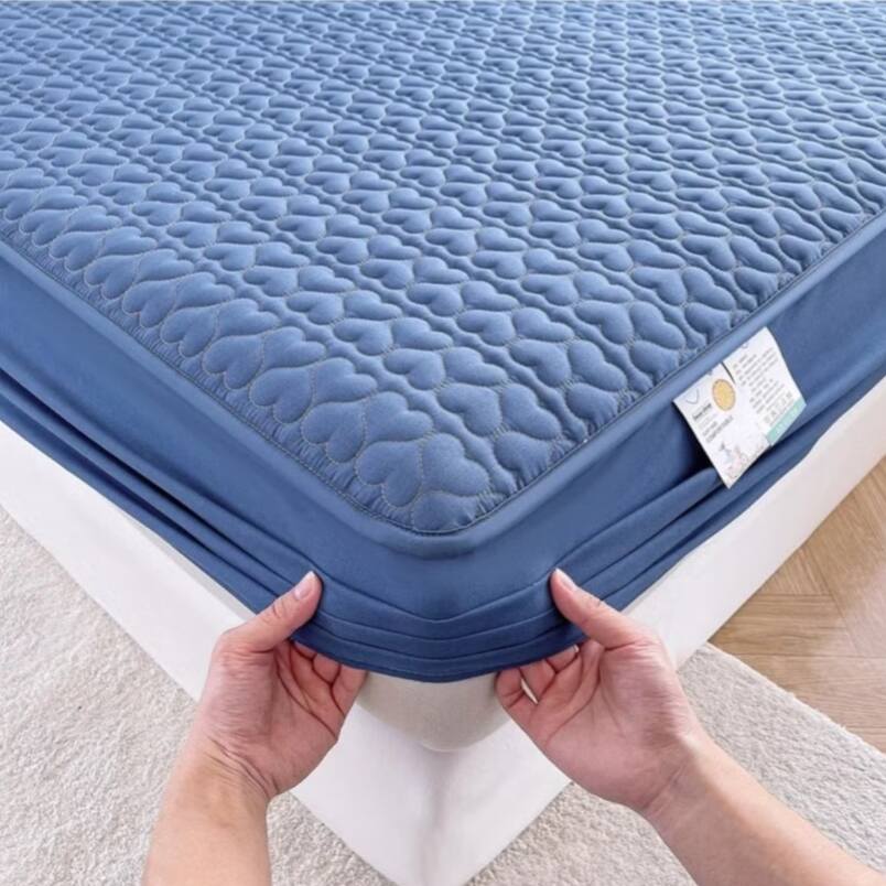 Huitich waterproof king size bedding topper in blue with quilted pattern and elastic edges being placed on mattress