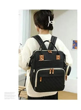 Black maternity backpack worn on back, quilted front panel and adjustable shoulder straps