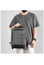 Light grey backpack worn by a person, showing front zip compartments