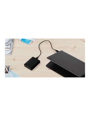Western Digital reliable backup storage device connected to laptop on wooden desk